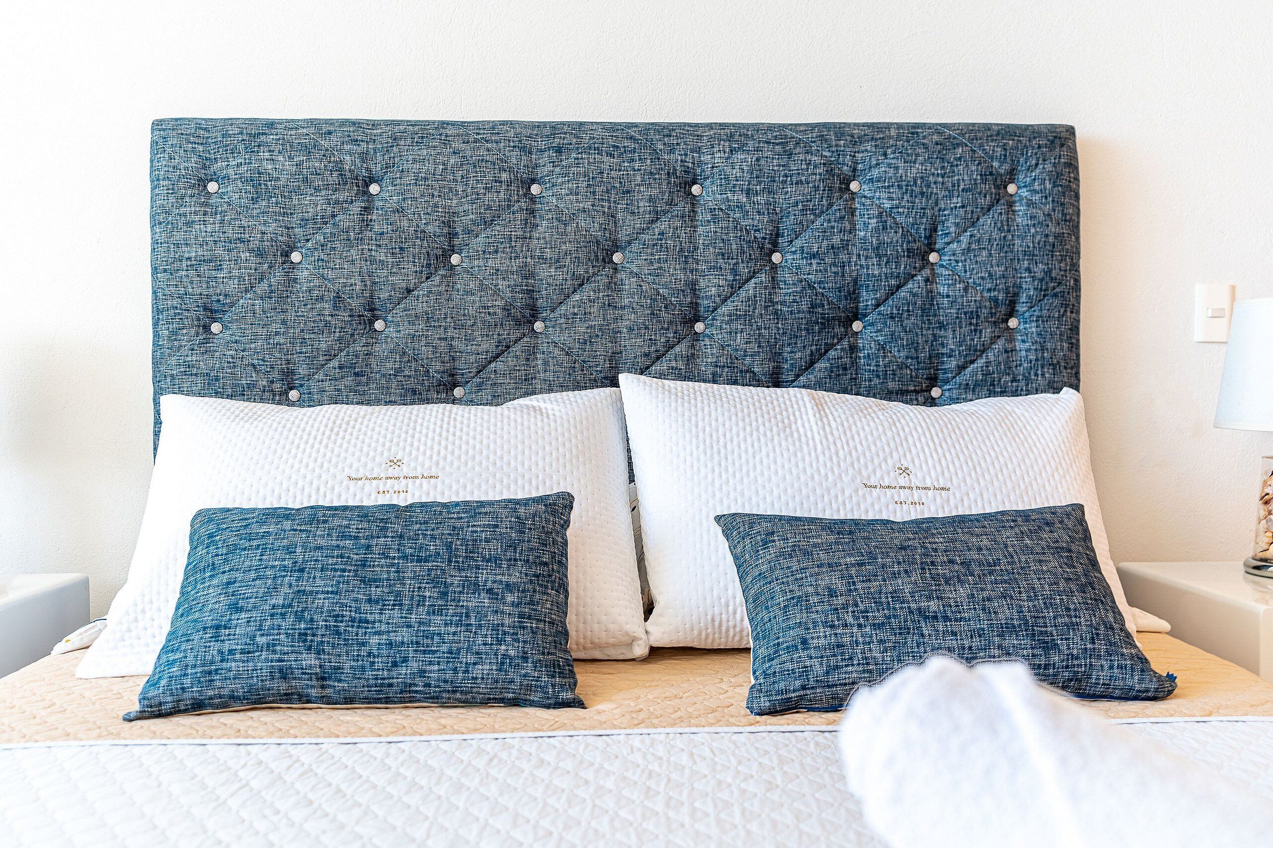 A bed with a tufted headboard, two pillows, and a white wall.