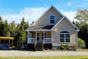 A two-story house with a porch, a covered patio, and a gravel driveway.