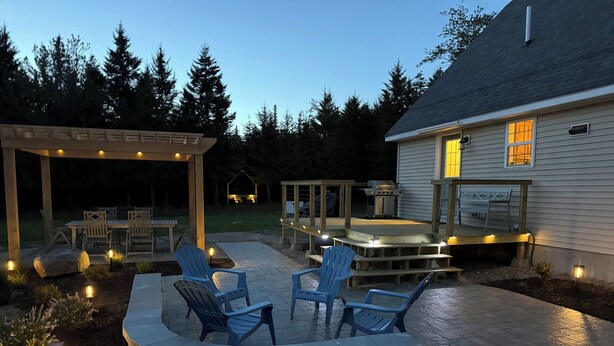 Un patio con mobiliario exterior, una parrilla y una terraza cubierta.