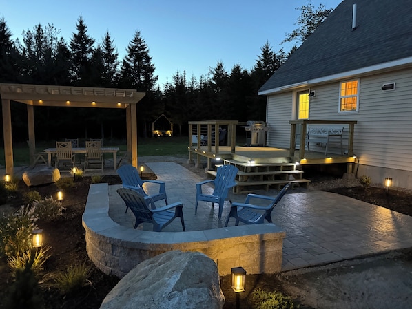A covered patio area with outdoor seating, a barbecue grill, and a house in the background.