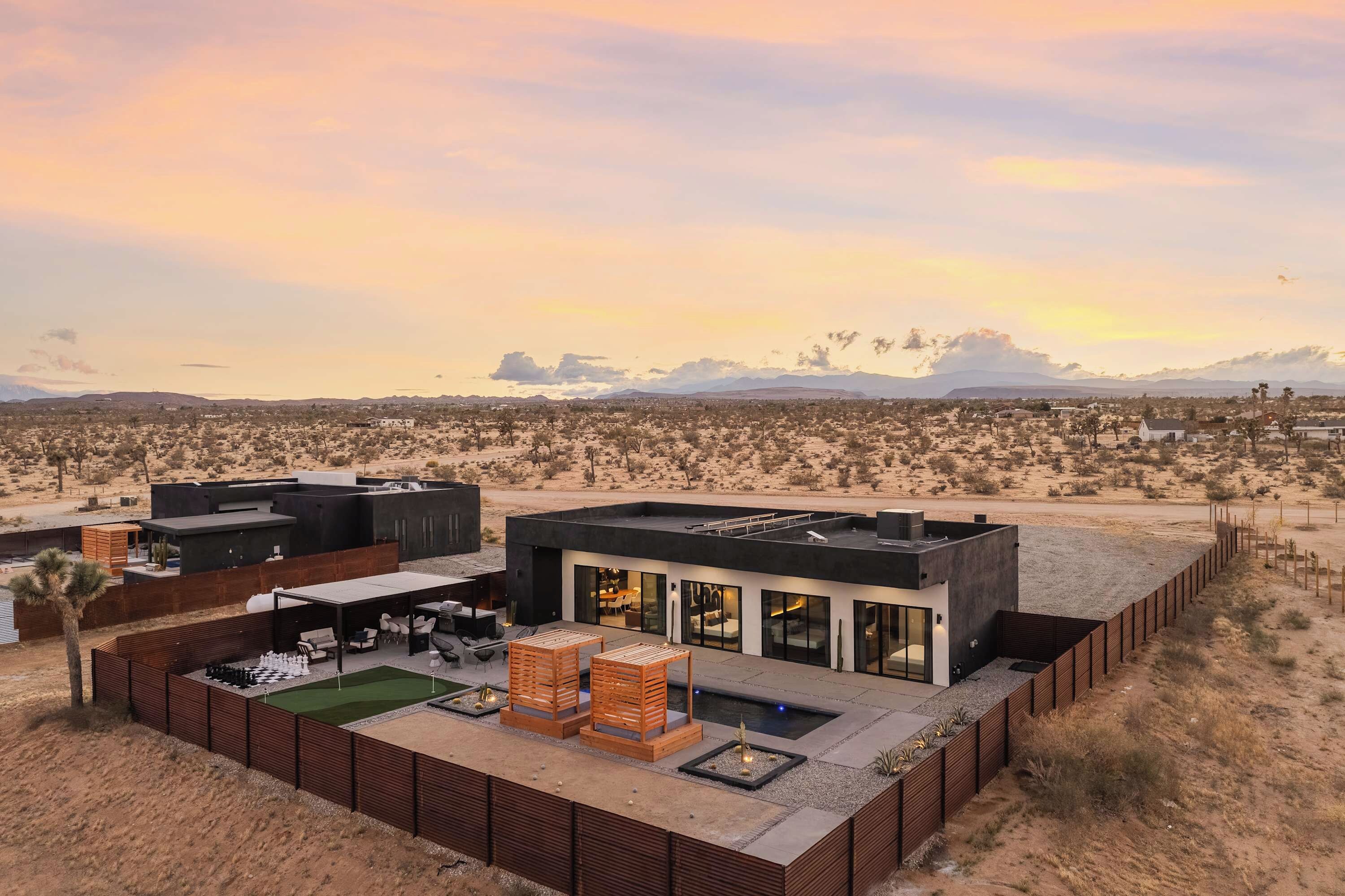A modern building with a flat roof, large windows, and a patio area with outdoor furniture.