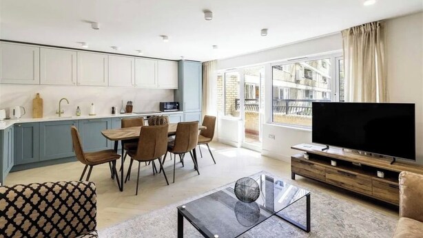 Un appartement moderne comprenant une cuisine, un coin repas, un salon et un grand téléviseur.