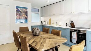 Une cuisine moderne avec des meubles blancs, une table à manger en bois et un élément décoratif mural.