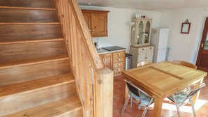 A wooden staircase leading to a kitchen with a dining table and chairs. - Kernyk (Penzance)