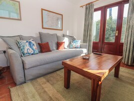 Una sala de estar con sofá, una mesa de centro de madera, un mapa en la pared y una puerta con cortinas.