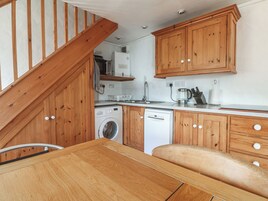Una cocina compacta con muebles de madera, lavadora, lavavajillas y microondas.