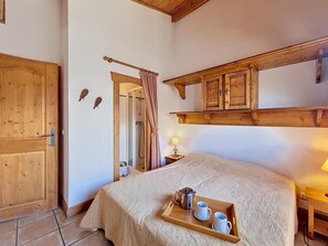 Ein Schlafzimmer mit einem hölzernen Bett, einem Holztablett mit Wasserkocher und Tassen, einem Holzschrank und einer Holztür.