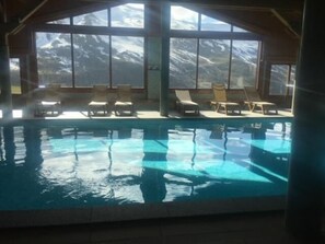 An indoor swimming pool with clear views of snow-capped mountains through large windows. - 100m from ski slopes, 3rd floor, swimming pool, balcony, tv, ski locker, 58m², Les Menuires (Les Menuires)