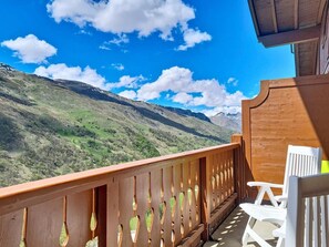 A balcony with a wooden railing, white chairs, and a view of a mountainous landscape. - 3rd floor, swimming pool, balcony, tv, ski locker, 58m², Les Menuires (Les Menuires)