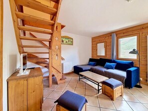 A wooden interior with a staircase, a sofa set, a table, and a radiator. - 3rd floor, swimming pool, balcony, tv, ski locker, 58m², Les Menuires (Les Menuires)