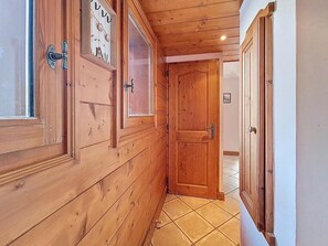 A wooden hallway with a door, a window, and a tiled floor. - 2nd floor, swimming pool, balcony, tv, ski locker, 50m², Les Menuires (Les Menuires)