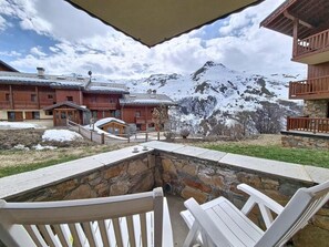 Ein Whirlpool mit weißen Stühlen, einer Steinwand und Blick auf schneebedeckte Berge und Gebäude.