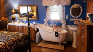 A room with a bathtub, a bed with patterned bedding, a dresser, a mirror, and a window with curtains. - 4B/4B Log Cabin Guesthouse includes an Old Western Town, Saloon & Firepit! (Cleburne)