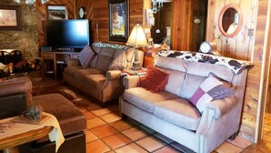 A cozy living room with a television, two sofas, a coffee table, and a fireplace. - 4B/4B Log Cabin Guesthouse includes an Old Western Town, Saloon & Firepit! (Cleburne)