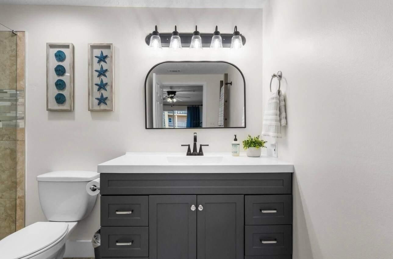 Une salle de bain avec un lavabo blanc, des meubles sombres, un miroir et une décoration murale représentant des étoiles.