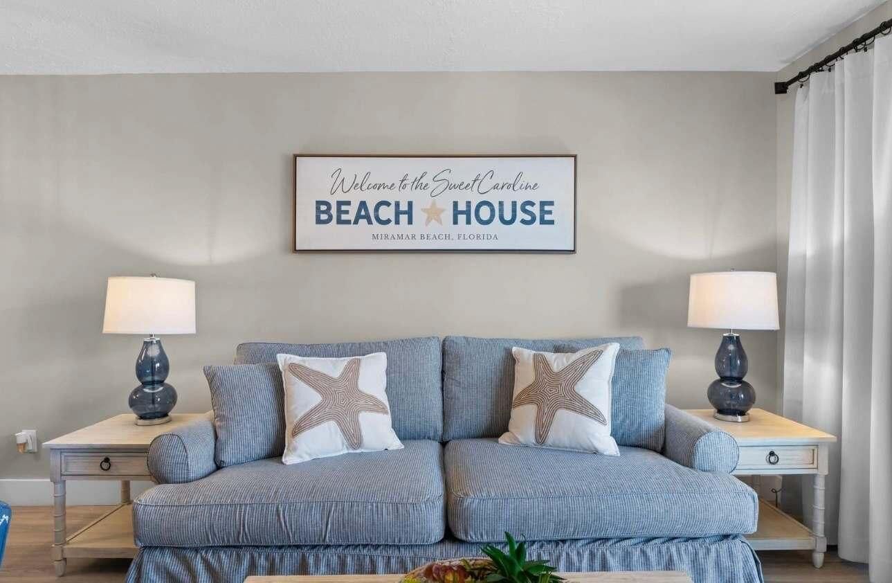 A room with a sofa, two nightstands, and a wall sign.