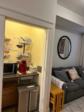 A compact living space with a kitchenette, a grey sofa, a mirror, and a small wooden table. - Cozy 2-bedroom apartment in beautiful Worcester with AC (Worcester)
