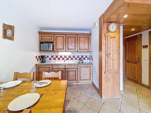 A compact kitchen with wooden cabinets, a microwave, and a tiled backsplash. - Floor -1, swimming pool, terrace, tv, ski locker, 32m², Les Menuires (Les Menuires)