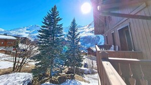 Ein hölzernes Gebäude mit Balkon, schneebedecktem Untergrund und immergrünen Bäumen.