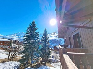 A wooden building with a balcony, snow-covered ground, and evergreen trees. - 3rd floor, swimming pool, balcony, tv, ski locker, 32m², Les Menuires (Les Menuires)