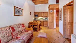 Ein gemütliches Wohnzimmer mit einer Couch, einem Esstisch und einer Küchenzeile mit Holzschränken und einer gefliesten Spritzschutzwand.