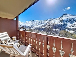 A balcony with white chairs, a brown railing, and a snowy mountain view. - 1st floor, swimming pool, balcony, tv, ski locker, 32m², Les Menuires (Les Menuires)