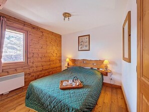 A wooden-paneled room with a bed, a window, a heater, and a framed picture on the wall. - 1st floor, swimming pool, balcony, tv, ski locker, 32m², Les Menuires (Les Menuires)