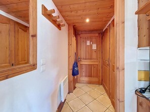 Ein schmaler Korridor mit Holzwänden und -türen, einem gefliesten Boden und einer blauen Tasche an der Wand.