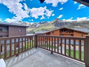Ein Balkon mit Blick auf eine Berglandschaft, Holzhäuser und einen klaren Himmel.