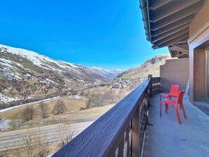 A balcony with a view of a valley and mountains, two red chairs, and a wooden railing. - 100m from ski slopes, 2nd floor, swimming pool, terrace, tv, ski locker, 32m², Les Menuires (Les Menuires)