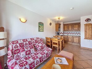 Ein gemütliches Wohnzimmer mit einem gemusterten Sofa, einem Esstisch und einer Küchenzeile mit Holdekor und einer gefliesten Spritzschutzleiste.