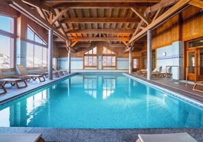 A pool area with wooden beams, lounge chairs, and large windows. - 100m from ski slopes, Ground floor, swimming pool, balcony, tv, ski locker, 32m², Les Menuires (Les Menuires)