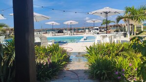 Zona de piscina con sombrillas, sillas y plantas.