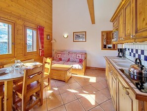 Ein Holzhütten-Interieur mit Esstisch, Stühlen, einer Couch und einer Küchenzeile.