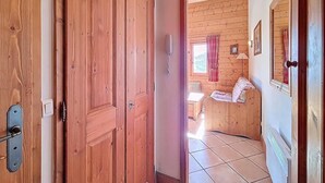 Una puerta de madera que da a una habitación con cama, ventana y radiador.