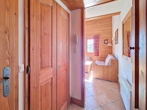 Eine Holztür, die zu einem Zimmer mit einem Bett, einem Fenster und einer Heizung führt.