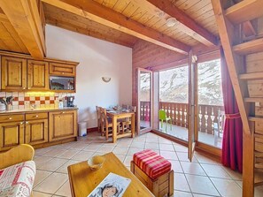 A wooden interior with a kitchen, dining area, and a balcony with a view. - 3rd floor, swimming pool, balcony, tv, ski locker, 40m², Les Menuires (Les Menuires)