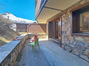 A stone building with a patio, a red chair, and a green chair. - Floor -1, swimming pool, terrace, tv, ski locker, 32m², Les Menuires (Les Menuires)