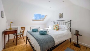 Una camera da letto con un letto, una scrivania, una sedia, un tavolino, una finestra e un quadro appeso al muro.