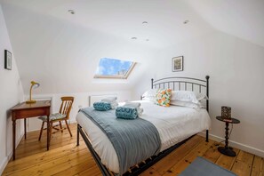 A bedroom with a bed, a desk, a chair, a small table, a window, and a picture on the wall. - Porto Bello - spacious home with sunny patio (Poole)