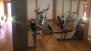 Una sala de gimnàstica amb equip de cardio i de musculació, sòls de fusta i grans miralls a les parets.