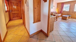 A wooden interior with a tiled floor, a wooden door, a small table, and a window with curtains. - 100m from ski slopes, Ground floor, swimming pool, balcony, tv, ski locker, 32m², Les Menuires (Les Menuires)