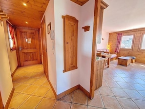 A wooden interior with a tiled floor, a wooden door, a small table, and a window with curtains. - Ground floor, swimming pool, balcony, tv, ski locker, 32m², Les Menuires (Les Menuires)