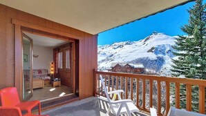 A balcony with wooden railings, two red chairs, and two white chairs. - 100m from ski slopes, Ground floor, swimming pool, balcony, tv, ski locker, 32m², Les Menuires (Les Menuires)