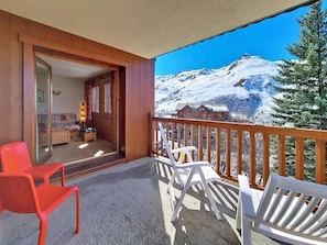 A balcony with wooden railings, two red chairs, and two white chairs. - Ground floor, swimming pool, balcony, tv, ski locker, 32m², Les Menuires (Les Menuires)