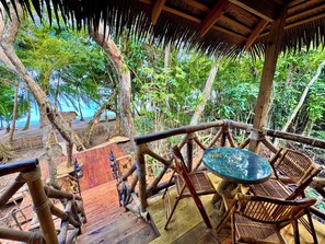 A wooden deck with a thatched roof, surrounded by lush greenery and overlooking a beach. - Great Green Wing Oceanfront Jungle Treehouse (Bocas del Toro Province)