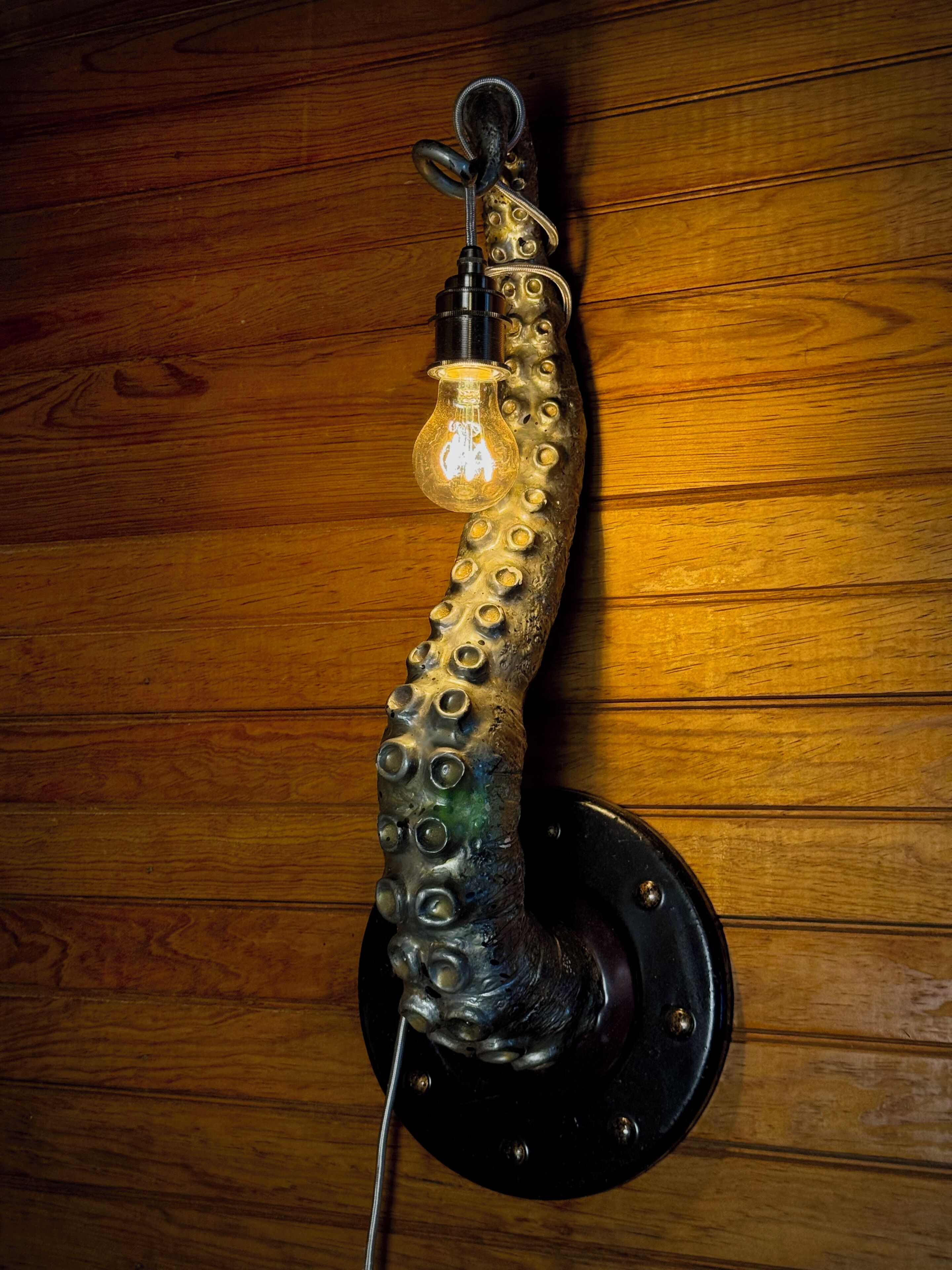 Een wandlamp met een opvallend octopusontwerp, een zichtbare lamp en een metalen voet.