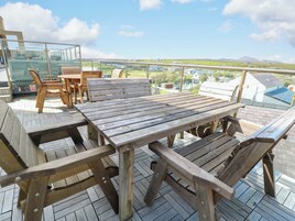 Una terraza de madera con una mesa y sillas, con vistas a un paisaje de edificios y colinas.