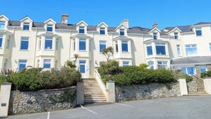 A row of white terraced houses with bay windows, a stone wall, and a clear blue sky. - Ewyn Y Don (Holyhead)