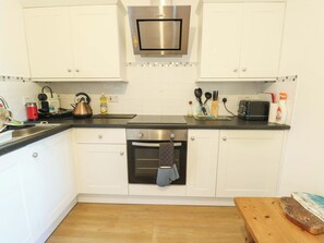 Eine Küche mit weißen Schränken, einem Edelstahlbackofen, einem Wasserkocher und einem Toaster.